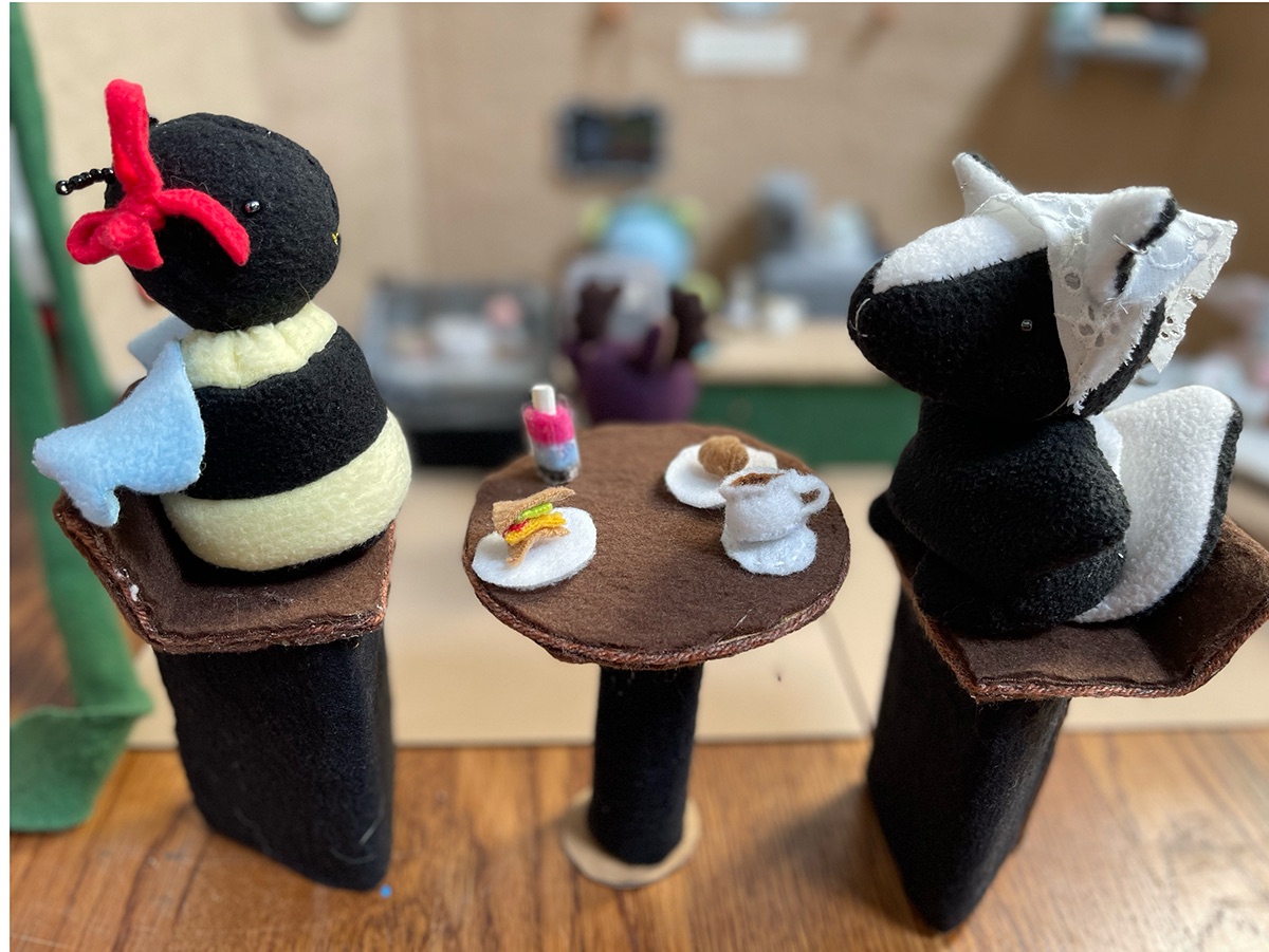 Two handmade café friends enjoying tiny treats at a table